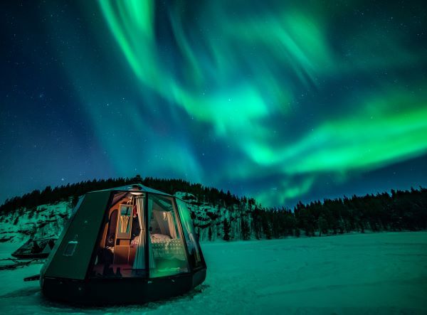northern lights over arctic glass igloo
